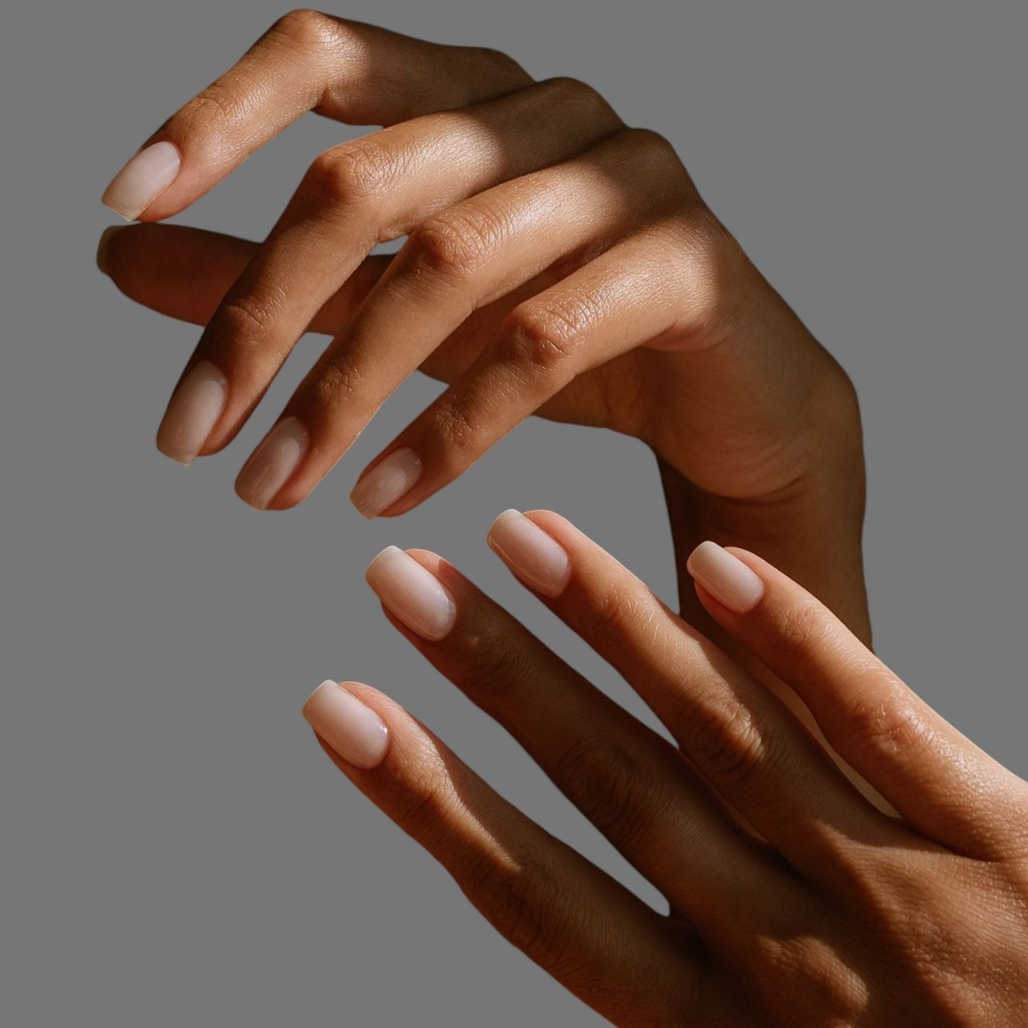 Neutral acrylic nails on grey background.