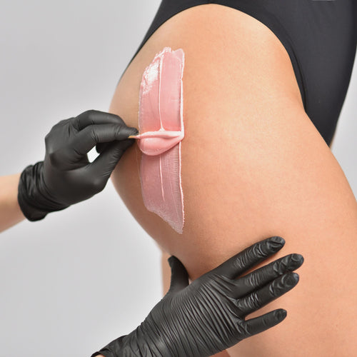 Demonstration of intimate waxing treatment using strip wax on the thigh
