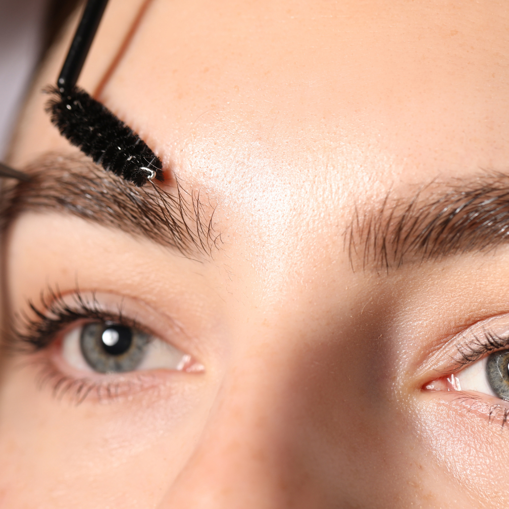 Close-up of a person applying airbrush product to their eyebrows.