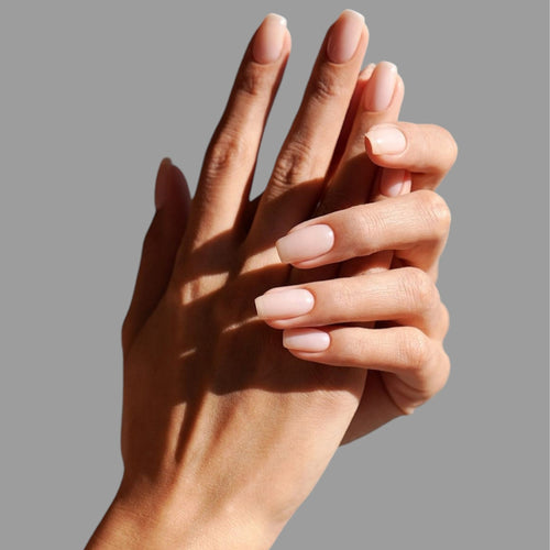 Close-up of two hands with light pink nail polish on a gray background