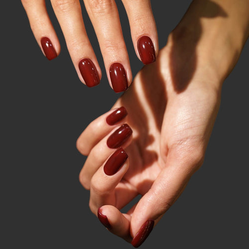 Close-up of hands with red nail polish on a dark background