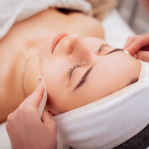 Facial on model with headband on, neutral background. 
