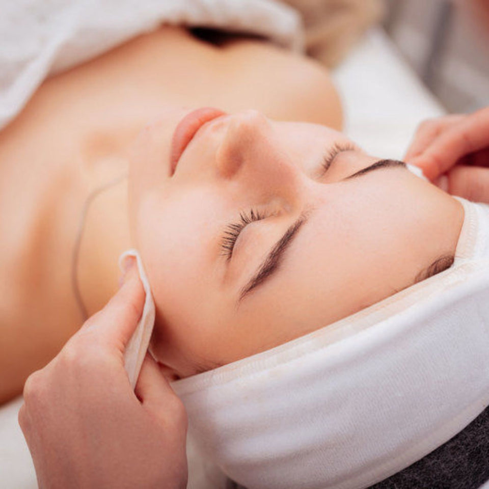 Facial on model with headband on, neutral background. 