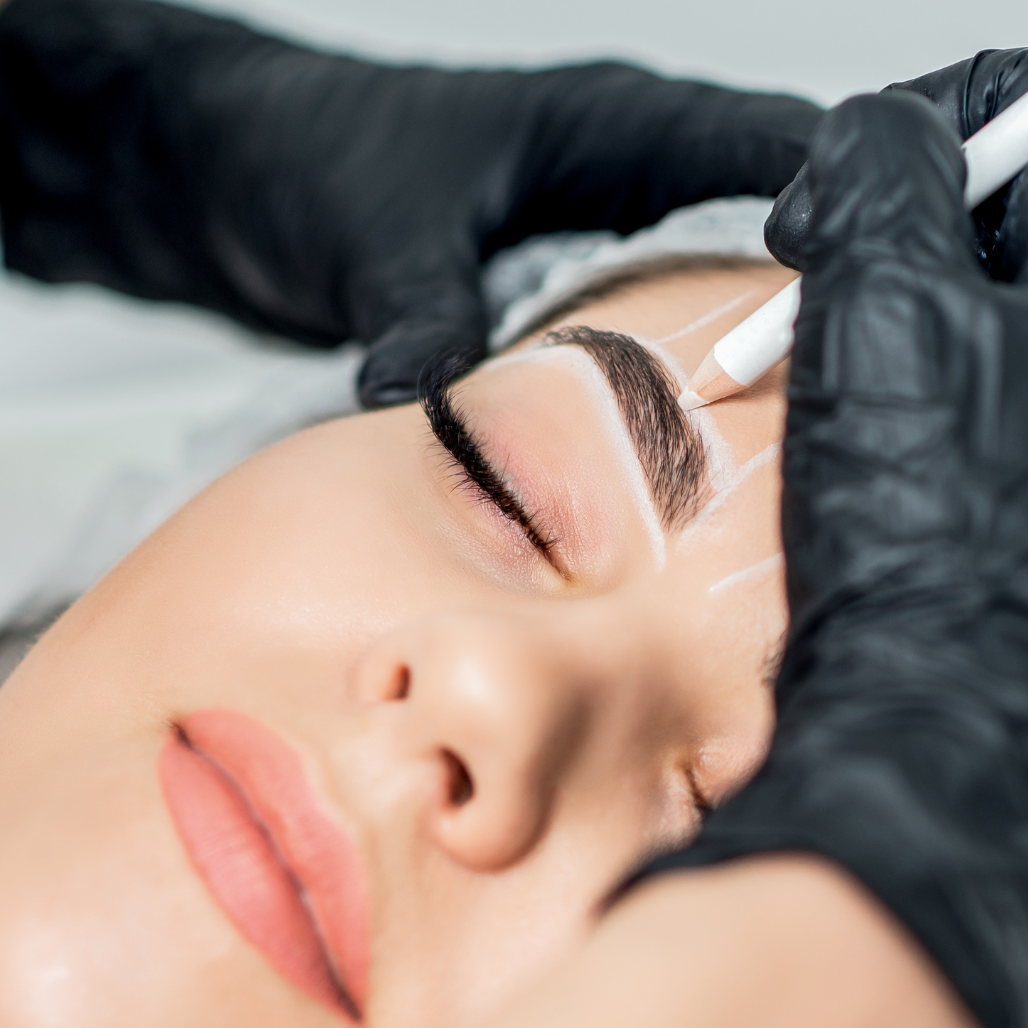 Person receiving full definition eyebrow treatment with black gloves on a neutral background