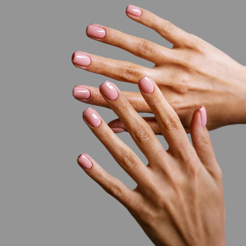 Close-up of two hands with pink nail polish on a gray background