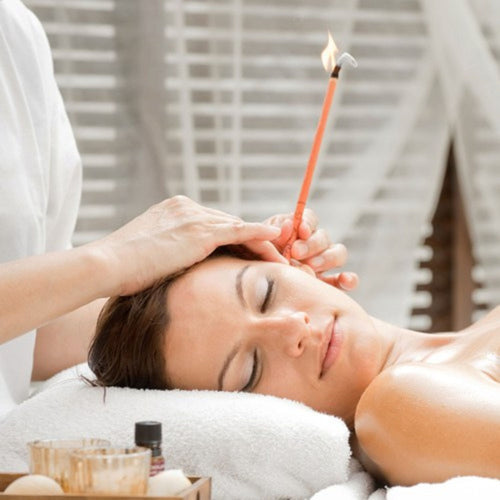 Hopi ear candling on model laid on bed with neutral background.